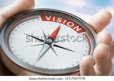 Hand holding a compass with needle pointing the word vision. Company or organization Statement values. Composite image between a hand photography and a 3D background.
