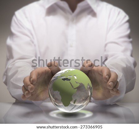 Image of a man in white shirt protect a glass earth with its hands. Earth concept for environmental protection or global business.