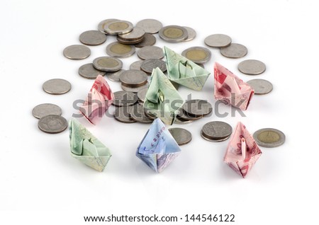 Thai money folded into the shape of a boat and coins isolated over white