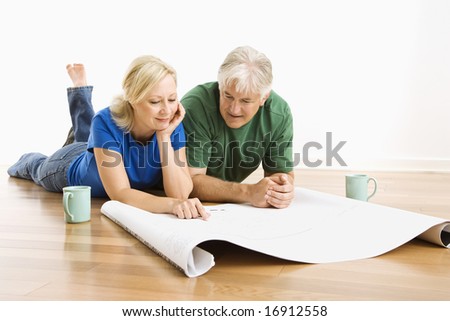 Middle-aged couple lying on floor looking at architectural blueprints together. Photo stock © 