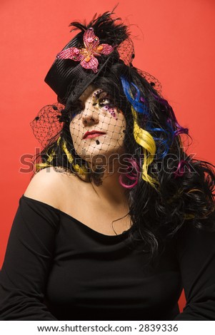 Portrait of Caucasian woman in unique makeup and clothing against red background.