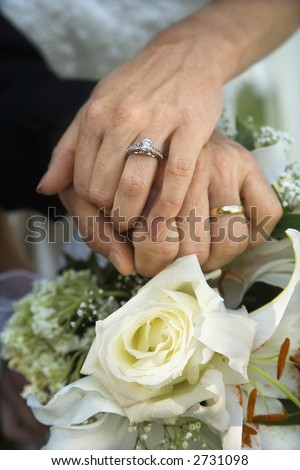 Close up image of bride and groom\'s hands overlapping.