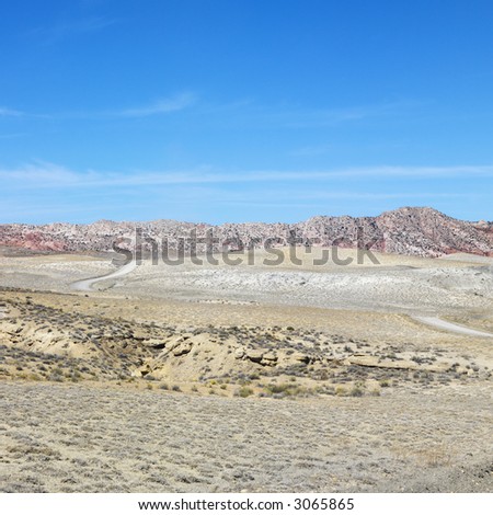 Desert land with rocky cliffs in background of Cottonwood Canyon.