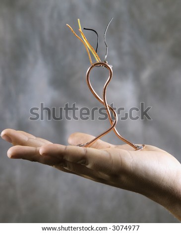 Male Caucasian adolescent hand holding wire sculpture.