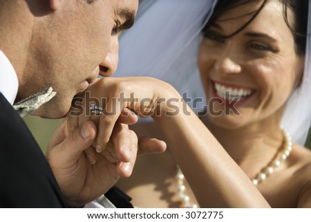 Caucasian prime adult male groom kissing hand of female bride.