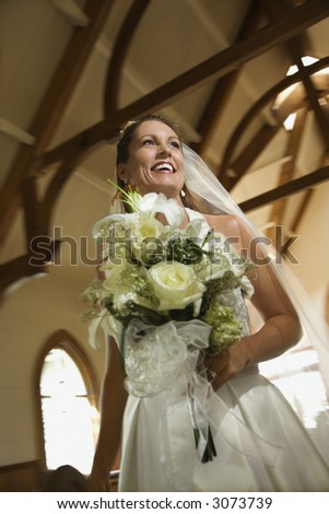Portrait of mid-adult bride holding bouquet leaving a church.