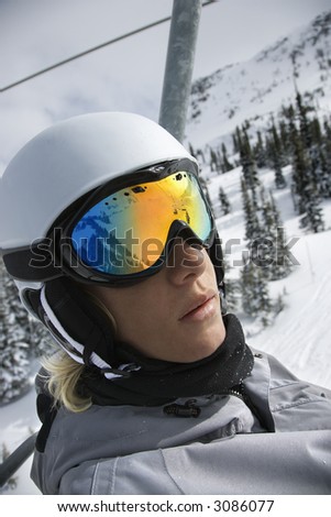 Caucasian teenage boy wearing helmet and goggles riding chair lift at ski resort in Whistler, British Columbia, Canada.