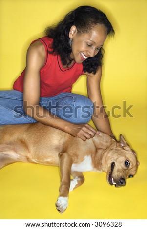African American prime adult female petting dog.