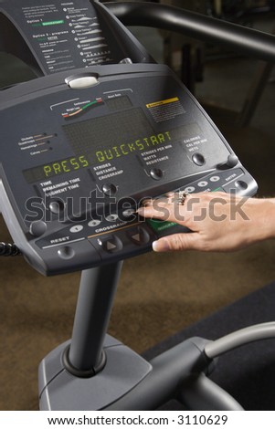 Prime adult Caucasian female setting up elliptical machine at gym.