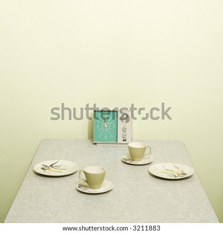 Retro 50's table setting with dishes coffee cups and vintage clock radio.