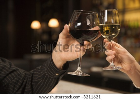 Mid adult Caucasian male and female hands toasting wine glasses.