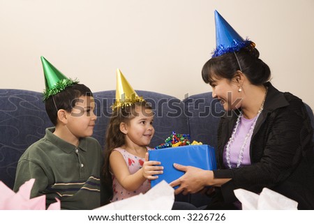 Mother giving present to daughter at birthday party.