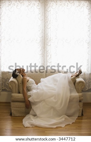 African-American bride lying on love seat.