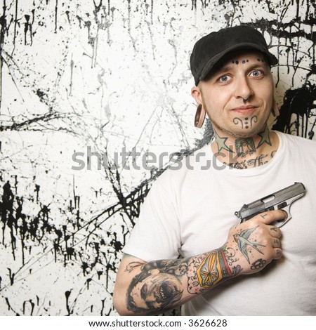 Caucasian tattooed man holding gun.