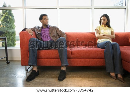 African American couple sitting on couch in dispute.