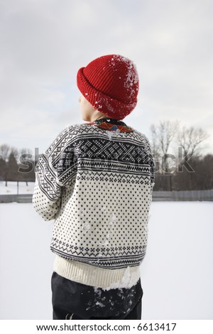 Back view of Caucasian boy wearing sweater and red winter cap.