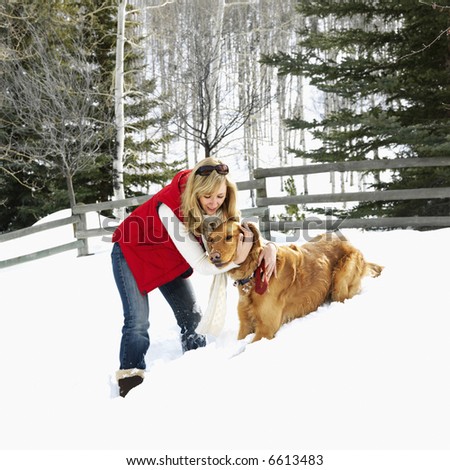 Woman with arms around dog in snow covered Colorado landscape.