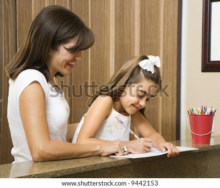 Hispanic mother helping daughter with homework.