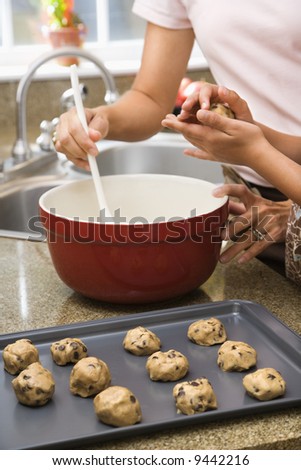 Close up of Hispanic mother and child in kitchen making cookies.