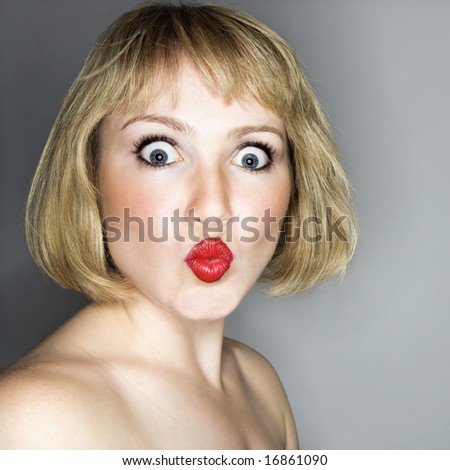 Portrait of young blonde caucasian woman who is looking at the viewer in surprise.