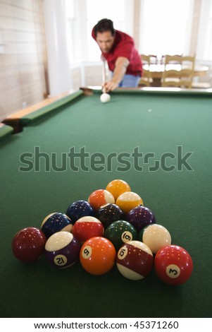 Racked pool balls as a man prepares to break. Vertical shot.