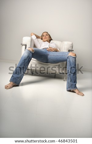 Low angle tilted view of a young woman relaxing in an armchair. Vertical shot.