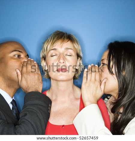 Businesspeople whispering into each ear of businesswoman.