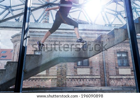 Running woman in black sports outfit, running up the stairs ,detail photo