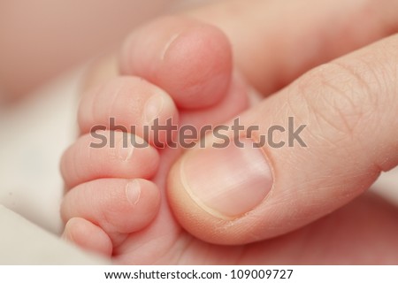 Mother touching baby\'s foot. Closeup.