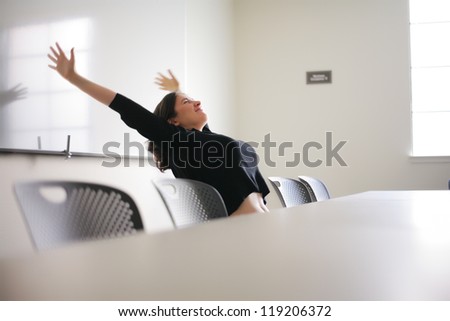 Happy young woman stretching in white office presentation room.