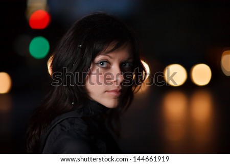 Portrait of beautiful young woman on dark night city street.
