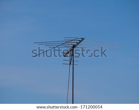 Old TV antenna over blue sky background.