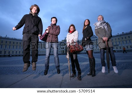Group of five trendy young people jumping in a city square