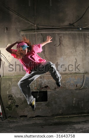Young dancer jumping on a street next to old grungy wall
