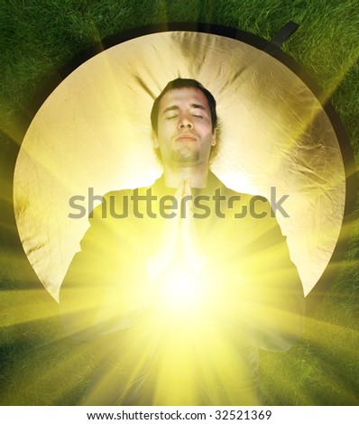 Young man meditating with rays of light coming out of his body.