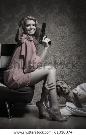 Sexy young adult woman with handgun sitting over man lying on floor and begging for mercy.
