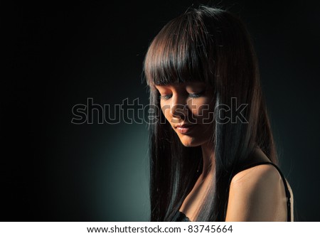 Portrait of beautiful model with long straight hair over dark background.