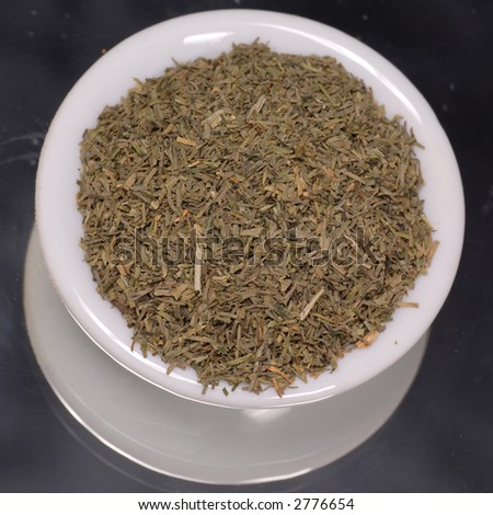 dried dill weed in white dispenser on black background