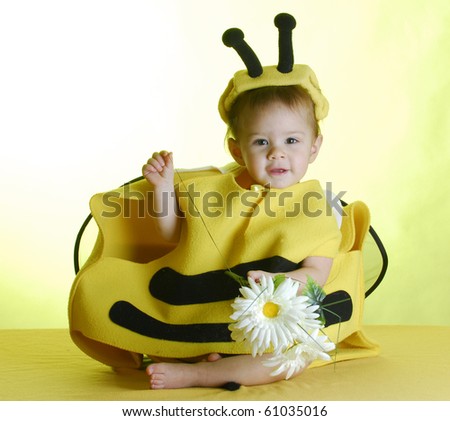 one year old child dressed up like a bee on yellow background