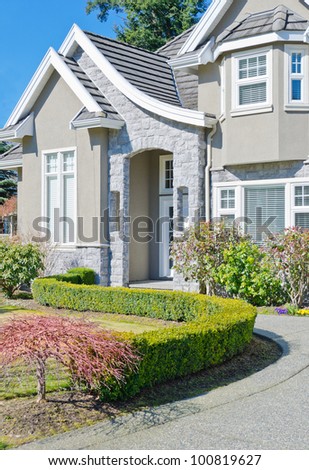 Fragment of the big luxury  home with nicely trimmed bushes at the doorway  in the suburbs of Vancouver, Canada