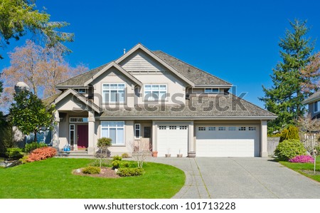 Luxury home with triple garage doors and the blue sky as a background in suburbs of Vancouver, Canada.