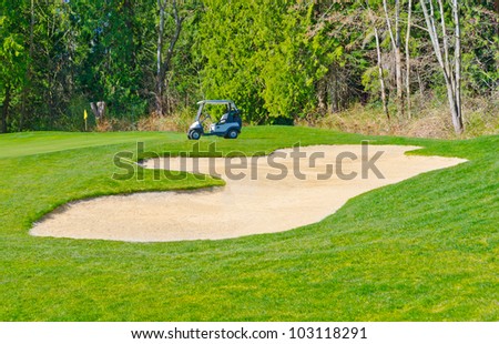 Sand bunker on the golf course with the golf cart at the back.