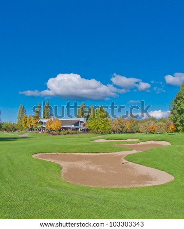 Golf place with gorgeous green and the sand bunker and dark blue sky with clouds as a background.
