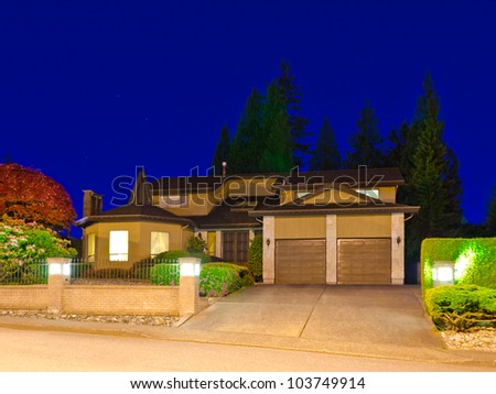 A big luxury house with double  garage doors in suburbs at dusk ( night ) in Vancouver, Canada