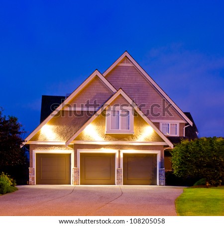 Big luxury house with the triple garage doors at dusk, night in suburbs of Vancouver, Canada