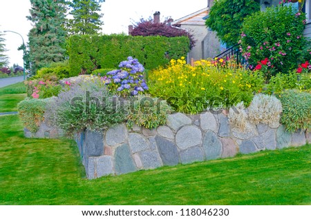 Some flowers and nicely trimmed bushes on the leveled front yard. Landscape design.