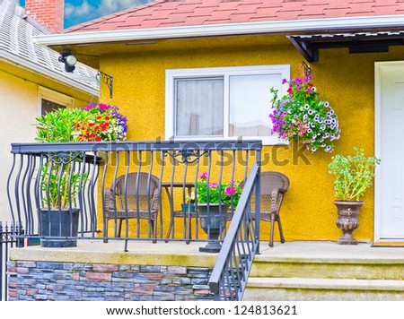 Nicely decorated front porch, patio with hanging baskets of flowers. Landscape design.