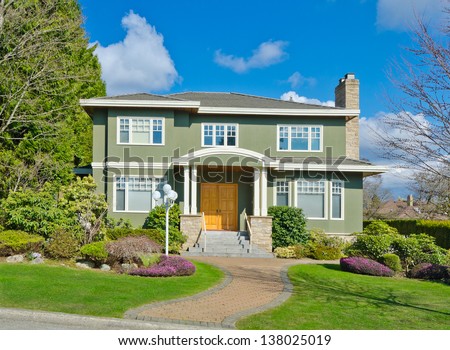 Big custom made luxury house with nicely paved long doorway and decorated and trimmed front yard in the suburbs of Vancouver, Canada.