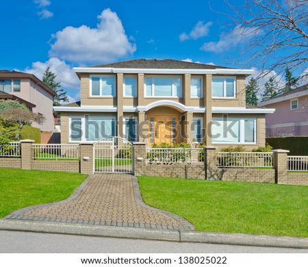 Big custom made luxury house with nicely paved long doorway and trimmed front yard in the suburbs of Vancouver, Canada. Vertical.