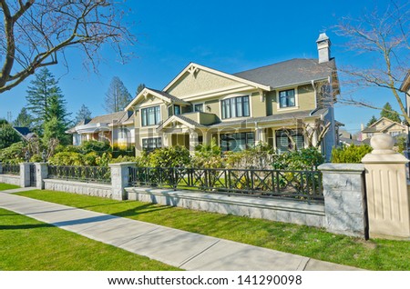 Fragment of the Luxury custom made house behind iron gates with long doorway at sunny day in Vancouver, Canada.